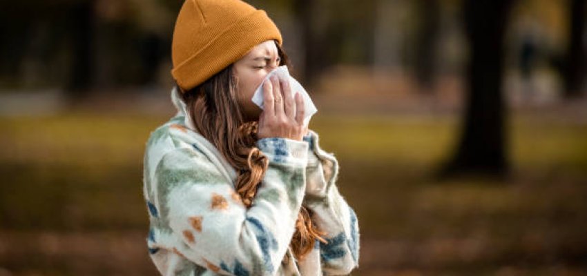 Woman sneezing in handkerchief at autumn