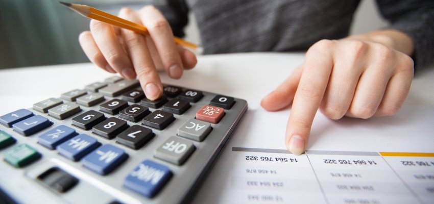 Closeup of accountant counting on calculator and working with table