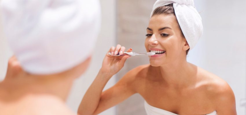 Young woman brushing teeth in bathroom